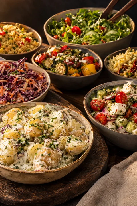 Diverse frisse salades als bijgerecht bij de barbecue, van aardappelsalade tot een groene salade.