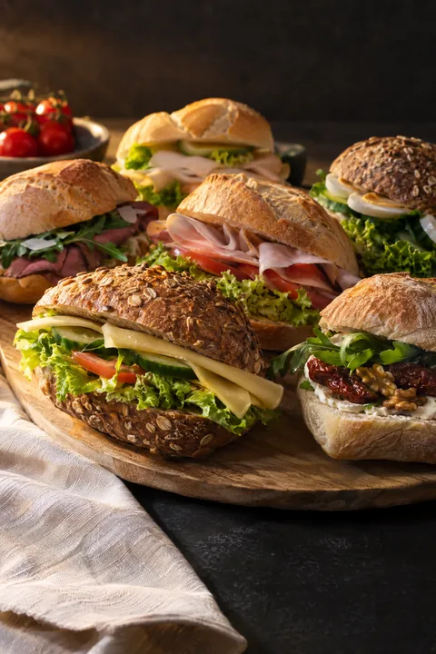 Ruime keuze belegde broodjes met kaas, vleeswaren en een vegetarische optie, samengesteld voor een gemengd gezelschap.